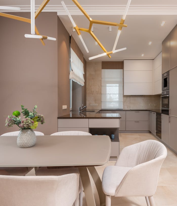 A stylish, open-plan kitchen and dining area featuring neutral tones, modern furniture, and elegant lighting.